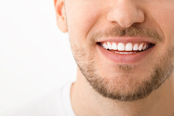 A beautiful man is smiling. a smile with white teeth. Close up image. White background with copyspace.