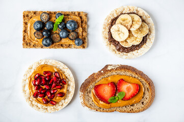 Various kind of open sandwiches with berries and fruits. Made from bread, such as wholegrain, rice crakers, crispbreads and different nut butter, such as peanut, crunchy cashew and almond butter