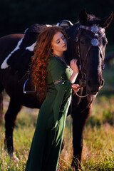 Naklejka premium Medieval woman princess in green dress sits astride black steed horse.