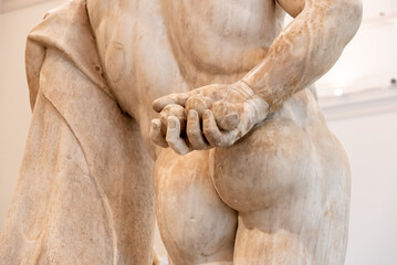 Close-up on ancient roman statue of naked man  whose hand full of small rocks is positioned on his...