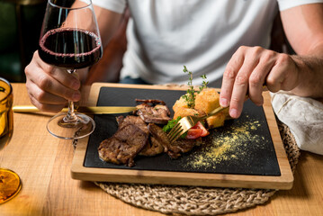 Man eating delicious beef dish complimented with red wine