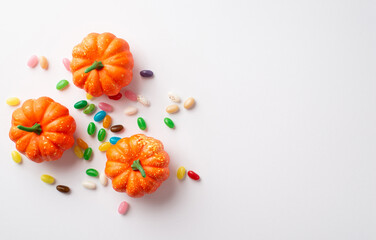Halloween concept. Top view photo of orange pumpkins and candies on isolated white background with copyspace - obrazy, fototapety, plakaty