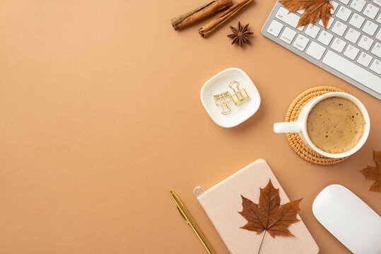 Autumn business concept. Top view photo of cup of coffee on rattan serving mat diary pen computer mouse keyboard cinnamon sticks anise yellow maple leaves and binder clips on isolated beige background