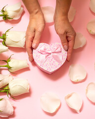 Gift box with rose flowers on the pink background.