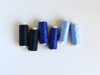 Six coils with threads on a white background. Threads of different shades of blue.