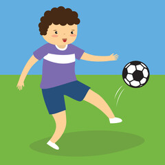 Boy kicking a ball on the grass