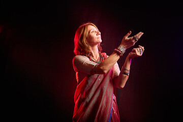 A beautiful European woman in a traditional Indian sari on a black background. Girl model posing in the studio