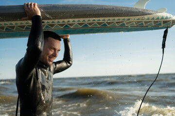A male surfer goes in for sports at sea uses a surfboard in a wetsuit