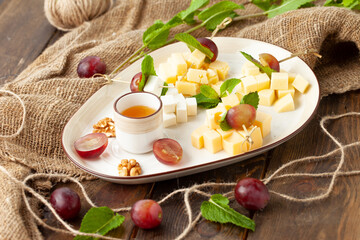 Assorted cheeses in a plate. On a wooden table.