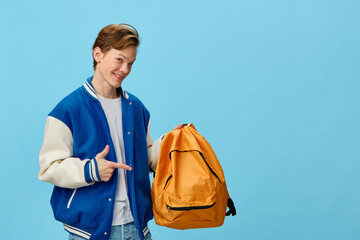 cute trendy guy in a bomber jacket holding an orange backpack pointing his finger at it