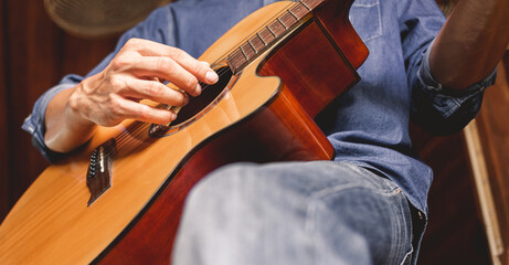 Close-up of the hands and fingers of a male musician playing an acoustic guitar.Musical guitar...