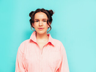Young beautiful smiling female in trendy summer pink overalls. Sexy carefree woman posing near blue wall in studio with two horns. Positive model having fun and going crazy. Cheerful and happy