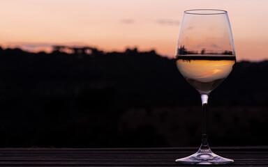 Elegant wine glass on a table outdoors, at sunset