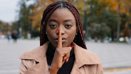 Close-up young confident mysterious african american woman standing outdoors showing silence...