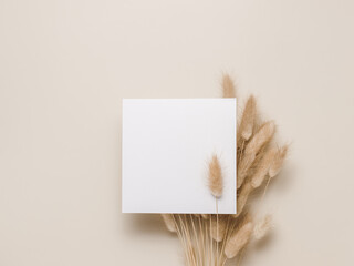 Blank paper card on dry lagurus grass top view, flat lay. Minimal aesthetic background card for greeting, invitation, business brand and social media. Neutral beige colors - obrazy, fototapety, plakaty