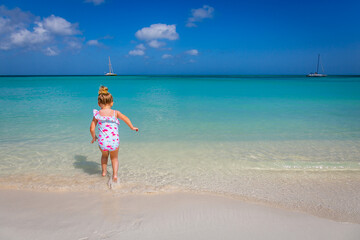 Fototapeta na wymiar Little girl having fun jumping on the caribbean beach, Aruba, Dutch antilles