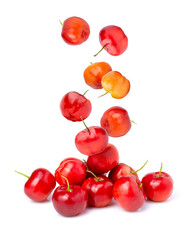 Acerola cherry falling to pile of red fresh fruit isolated on white background.
