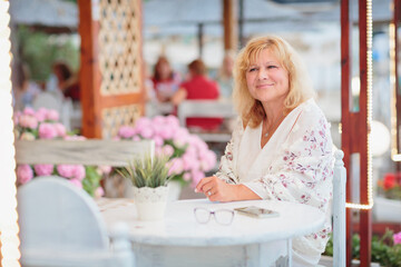 Portrait of woman sitting on the terrace of a beach cafe on a summer sunny day