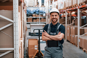 Standing and posing. Employee in uniform is working in the storage at daytime