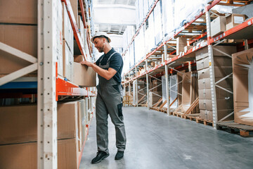 Taking out the box. Employee in uniform is working in the storage at daytime