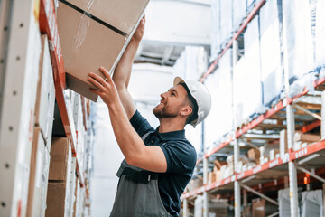 Taking out the box. Employee in uniform is working in the storage at daytime