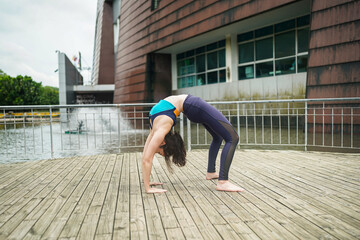 Young sporty attractive woman practicing yoga, doing yoga exercise with friend, yoga pose, working out, wearing sportswear, pants and top, outdoor full length