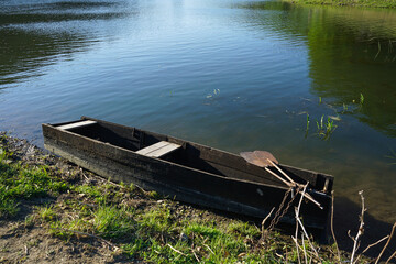 Obraz premium An old wooden fishing boat near the shore of the river. Beautiful nature