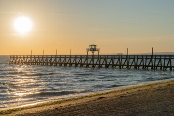Luc-Sur-Mer, France - 08 03 2022:  View of a wooden pier in front of the sea, a colorful sunrise...