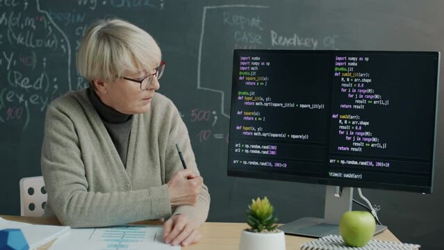 Programming school teacher explaining software coding pointing at computer screen and speaking during video lesson in messenger. Remote education and IT class concept.