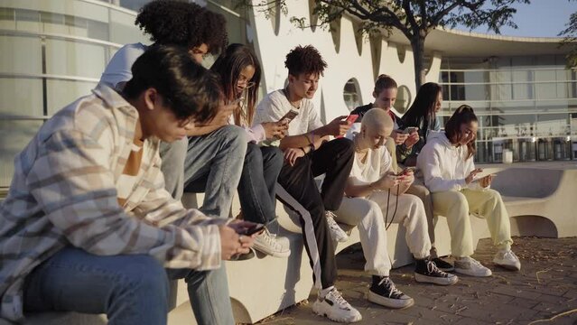 Group of young technology addicts using mobile smartphone outdoor. Multi ethnic millennial generation no social with new trends social media apps. Lens flare