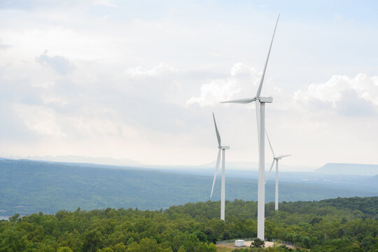 Picture of a wind turbine field at a renewable energy generating station. The background is a beautiful sky and mountains.