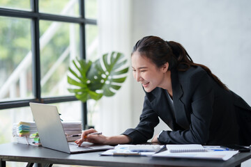 Beautiful Asian businesswoman hurriedly checks at his desk with his laptop computer to check urgent document.