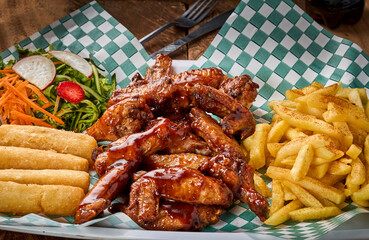 foto vertical de alitas bbq  con papas y ensalada