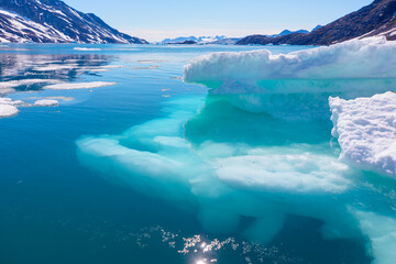 Melting giant icebergs by the coast of Greenland, on a beautiful summer day - Melting of a iceberg and pouring water into the sea - Greenland