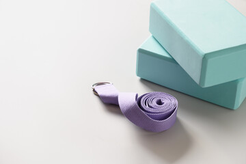 Green yoga blocks and violet belt on gray background. Yoga practice, relaxation and meditation...