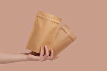 Woman's hands hold cardboard packages for tea or snacks on a beige background. Tea branding and...