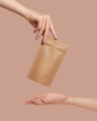 Woman's hands hold cardboard packages for tea or snacks on a beige background. Tea branding and...