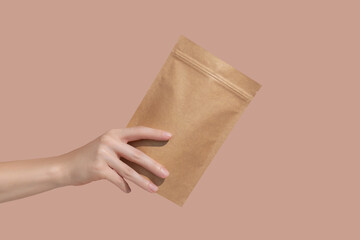 Woman's hands hold cardboard packages for tea or snacks on a beige background. Tea branding and packaging mockup.