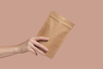 Woman's hands hold cardboard packages for tea or snacks on a beige background. Tea branding and...