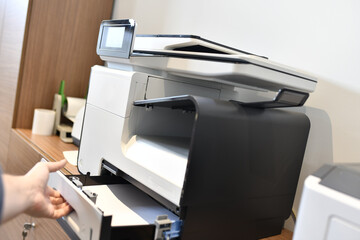 man's hand changing the paper to a printer in the office
