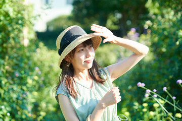 強い日差しを手で遮る女性