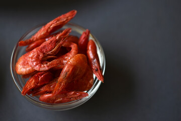A delicious appetizer of red shrimp with spices. Peppered shrimp in a salad bowl on a black background. Spicy seafood appetizer.