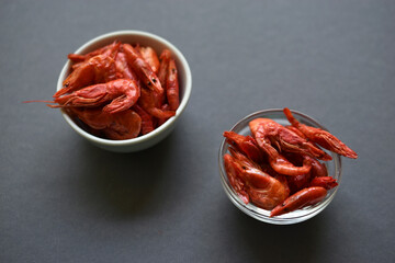 A delicious appetizer of red shrimp with spices. Peppered shrimp in a salad bowl on a black background. Spicy seafood appetizer.