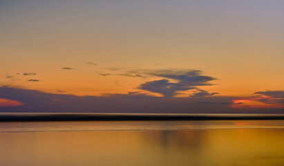 Golden sunset in the sea. Background or screensaver idea. Image has grain or blur, noise, and blurry focus when viewed at full resolution. (Shallow depth of field, slight motion blur)