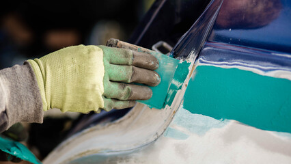 putty on a spatula by a body repair master, puttying a car body.