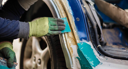putty on a spatula by a body repair master, puttying a car body.