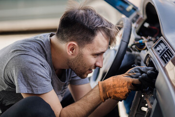 male auto mechanic repairs a car interior panel, dismantling the heater radiator heater deflectors...