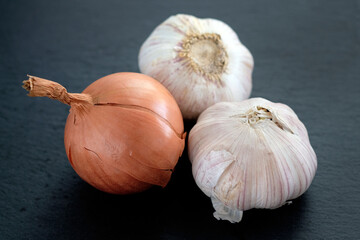 Head of onion and garlic on a black background. Onion and two heads of garlic close-up. Vegetables in the husk