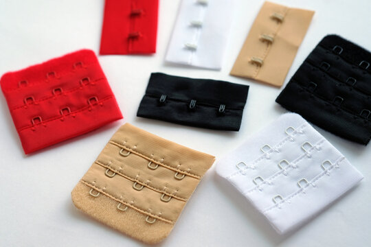 colored hooks on a fabric basis. Colored bra clasps on a white background top view. Accessories for sewing underwear.