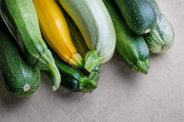 Green and yellow zucchini harvest in wooden box at green garden background. Copyspace